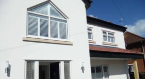 Outside view of large white house with indoor shutters