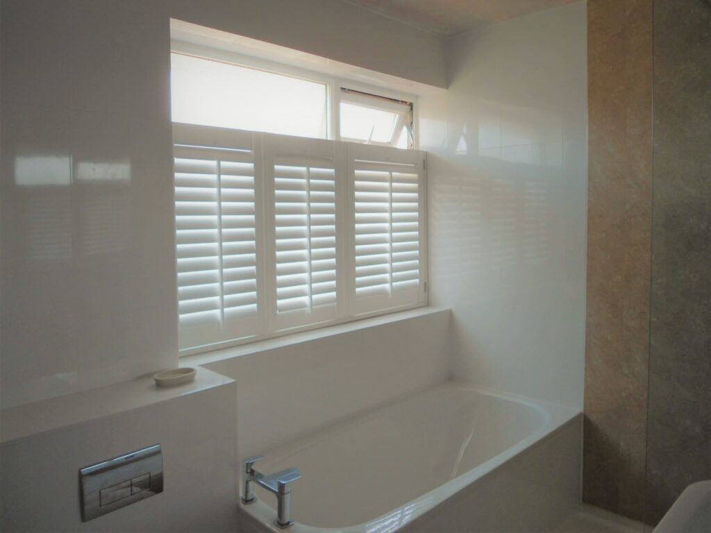 Stone bathroom with white cafe shutter