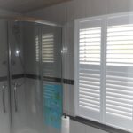 Shower room with white shutters close but letting light through