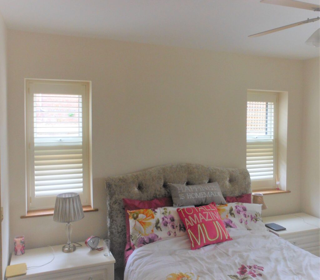 Bedroom with small windows and white shutters