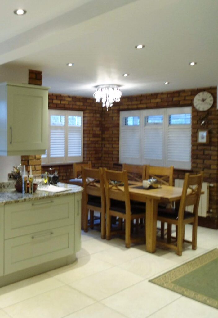 Sage green kitchen with white shutters