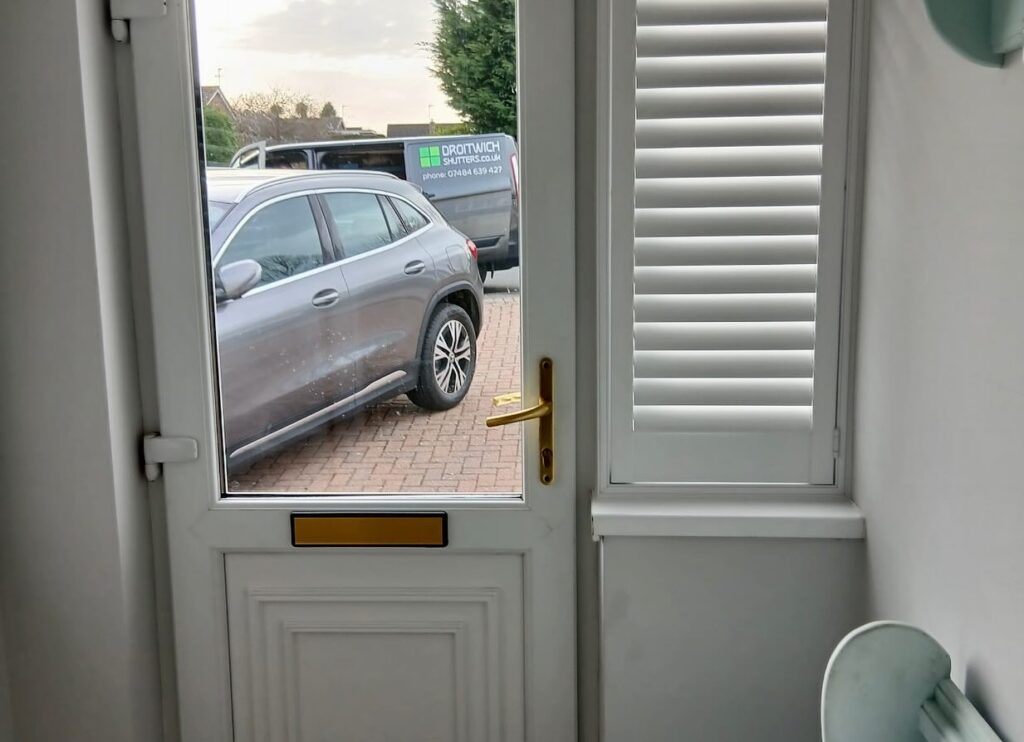 a small white shutter near the front door in a porch