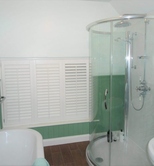 Green bathroom with low window and white shutters