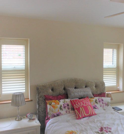 Bedroom with small windows and white shutters