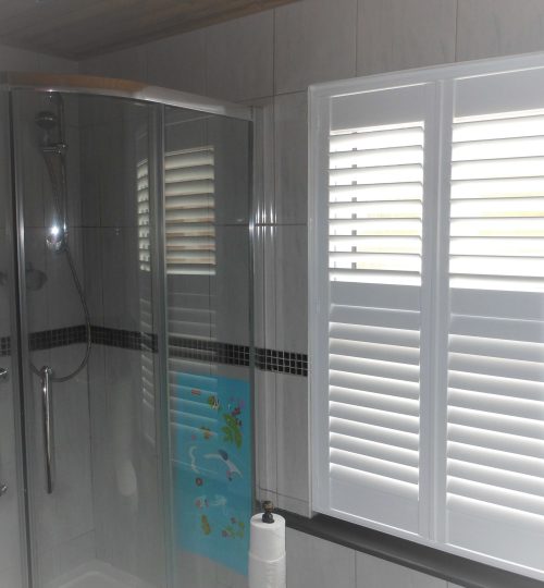 Shower room with white shutters close but letting light through