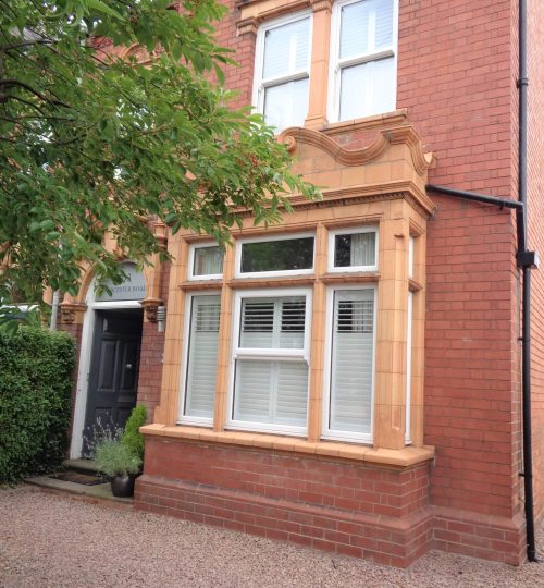 outside view of a box bay window in a Victorian home with white indoor shutters