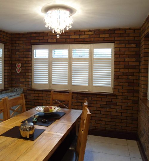 Brick walled dining room with white shutter