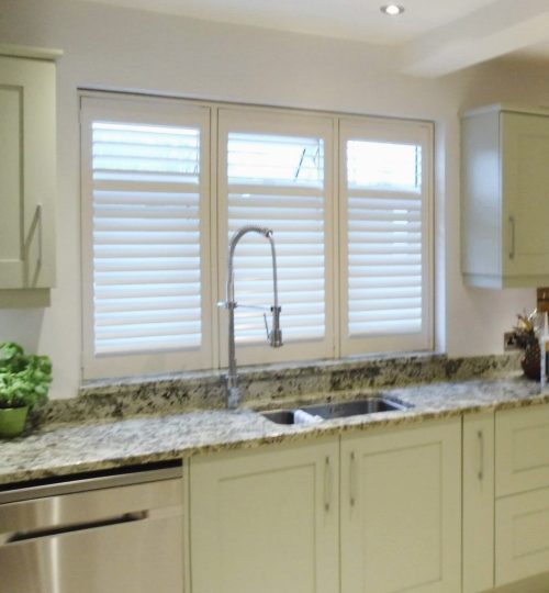 Sage green kitchen with white shutters