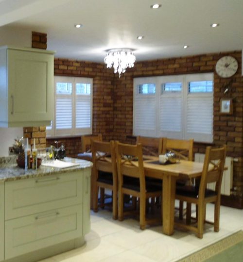 Sage green kitchen with white shutters