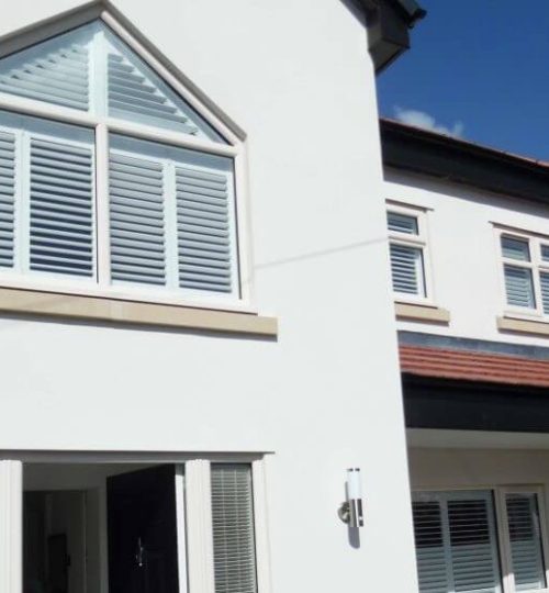 Outside view of large white house with indoor shutters