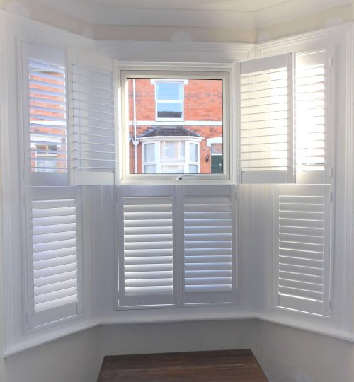 indoor view of white lounge shutters with one open door